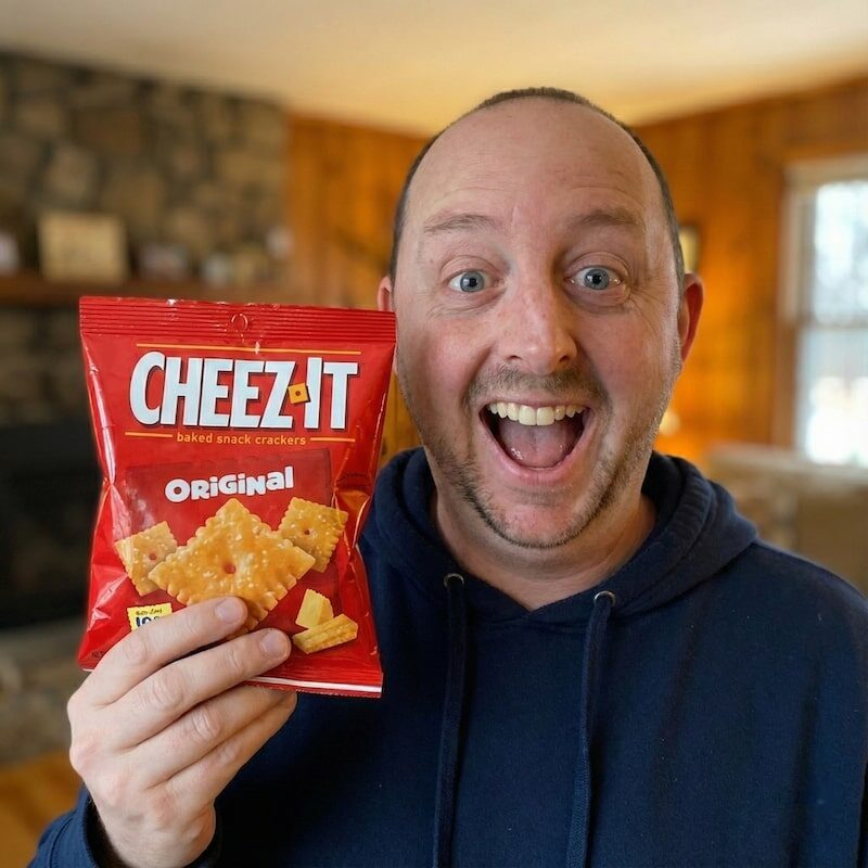 Corey Maass in a sweatshirt holding a bag of Cheez-its.